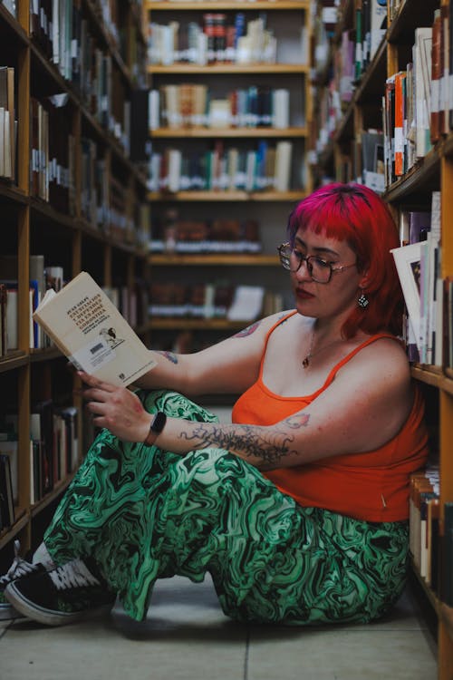 A woman with red hair sitting in a library with books