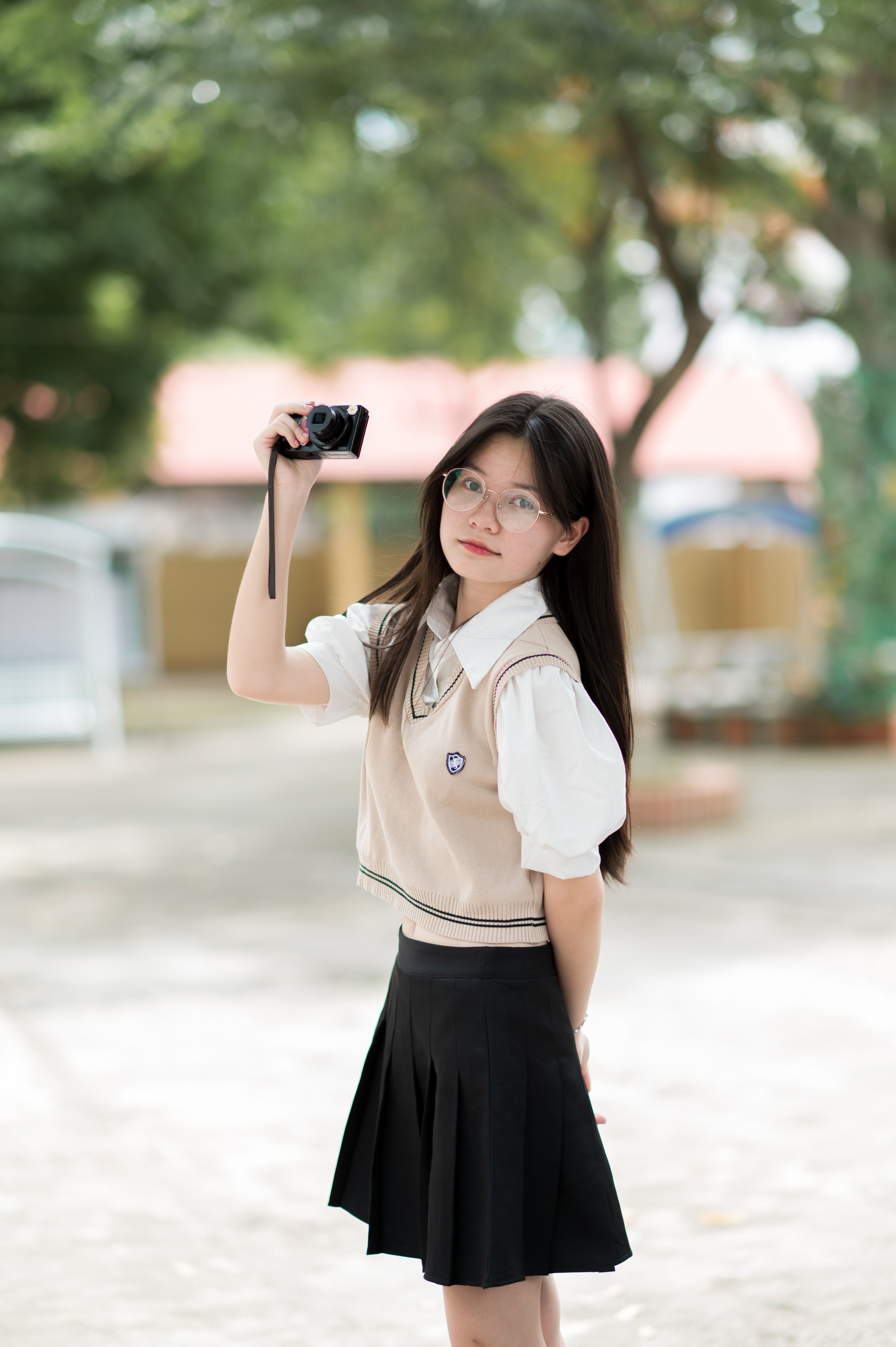 Portrait of a young woman with glasses holding a camera outdoors in Lạng Sơn, Vietnam.