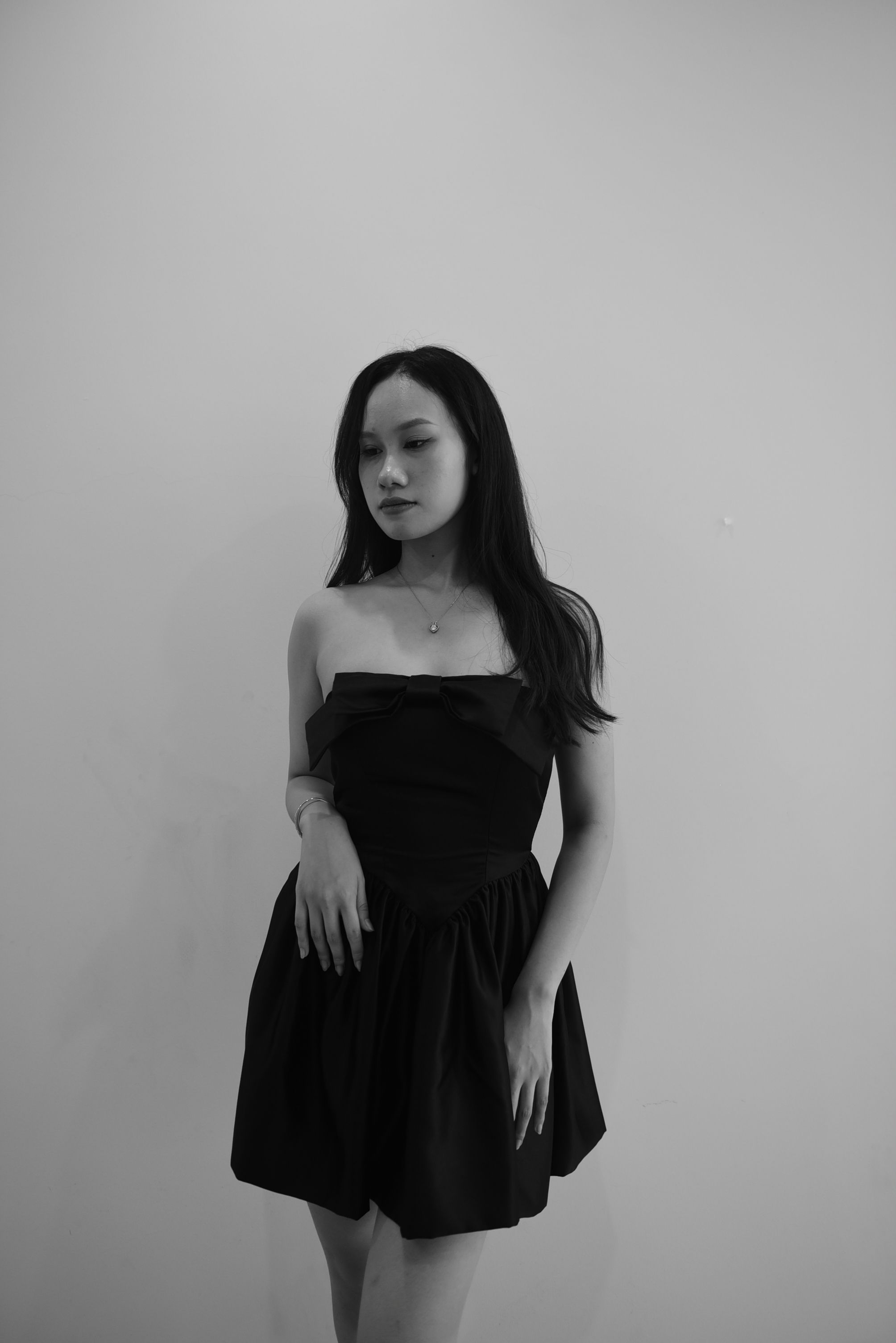 Elegant woman in a black mini dress posing in a studio black and white portrait.