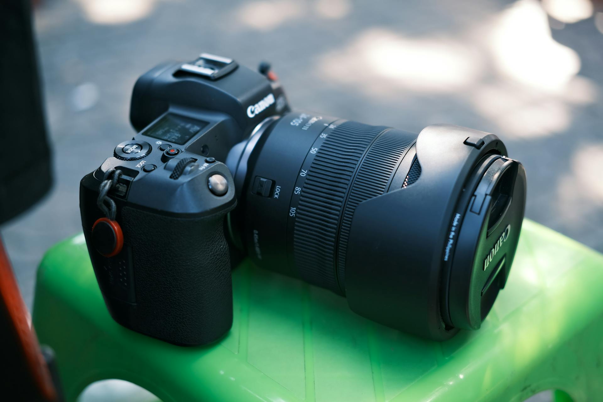 DSLR camera featuring a zoom lens, lens cap, and display screen on a bright background.