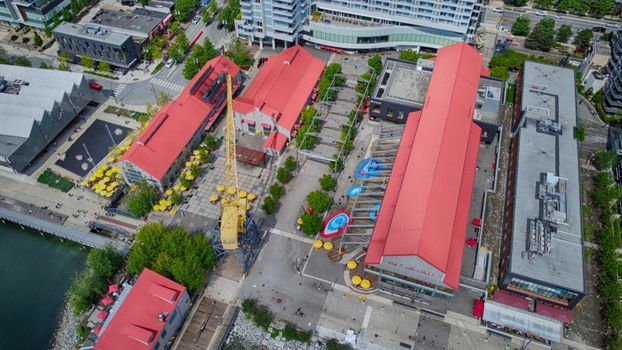 Scenic aerial view of the vibrant Shipyards District in North Vancouver, BC, showcasing red rooftops and bustling waterfront.