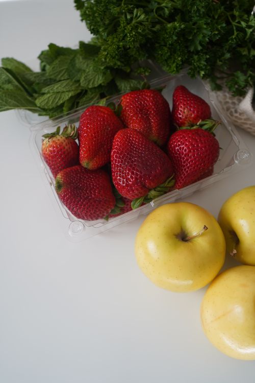 Free A collection of fresh strawberries, apples, and herbs on a white table. Stock Photo