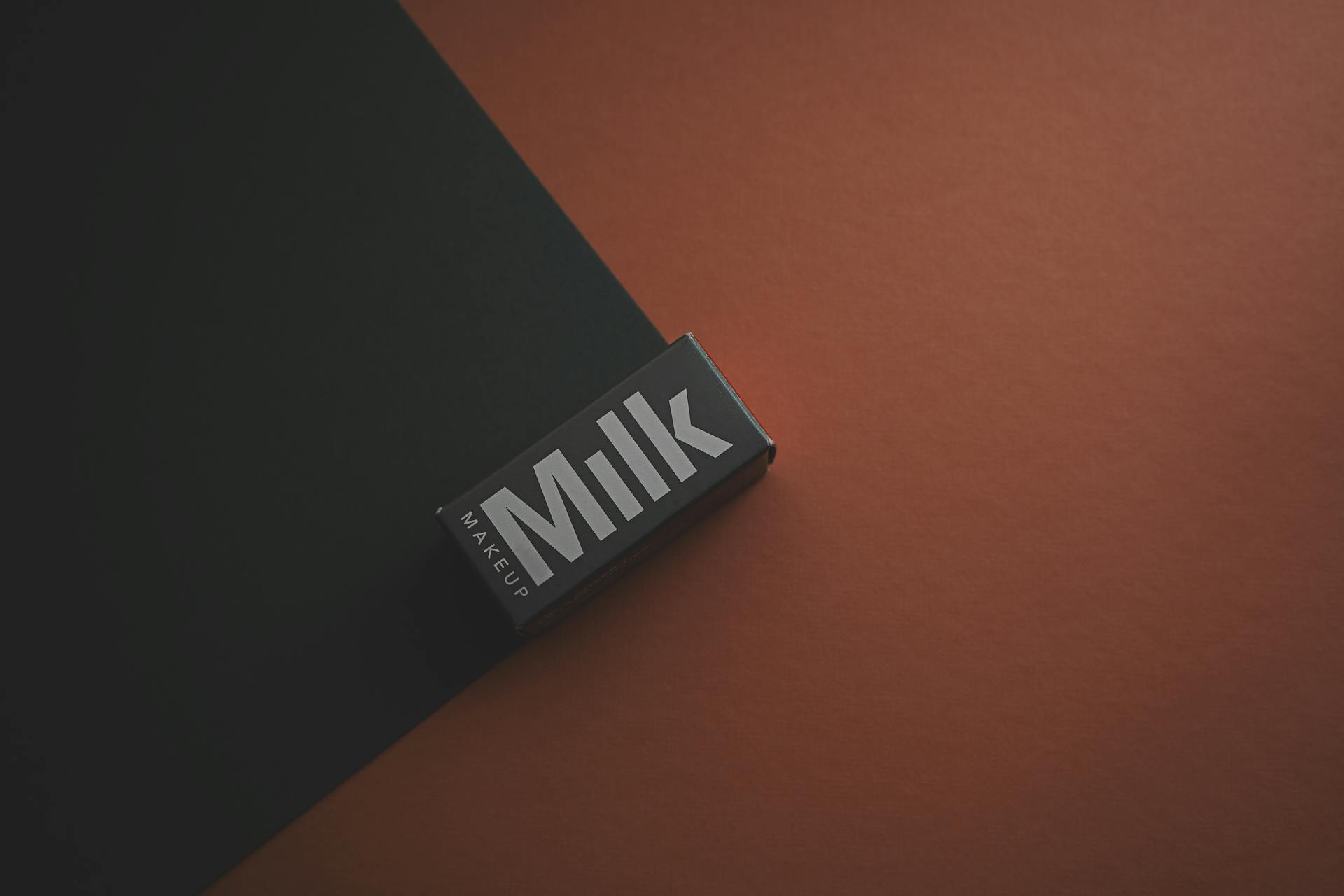 Close-up of a Milk Makeup box on a dark background, showcasing minimalist packaging design.