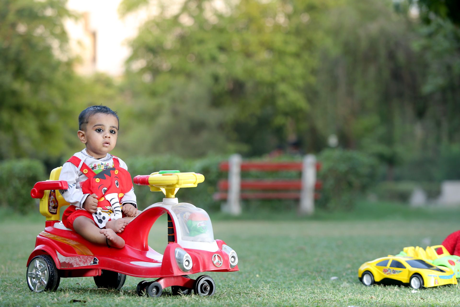 A cute child enjoying a ride-on toy car in an outdoor garden, embodying innocence and joy.