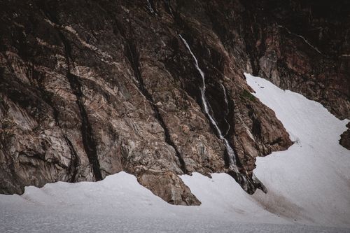 Free A serene snowy mountain landscape with a small waterfall cascading down rocky cliffs. Stock Photo