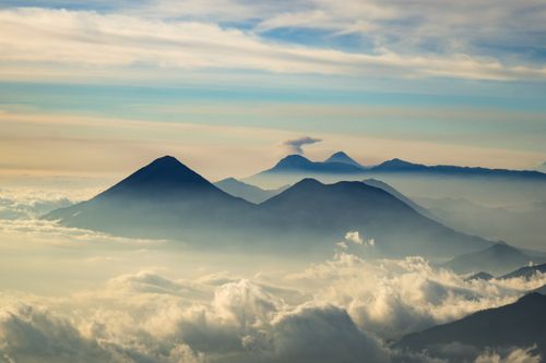 Free Scenic view of majestic mountains above fluffy white clouds during a tranquil sunrise. Stock Photo