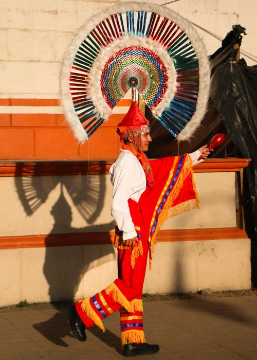Free Brightly dressed performer in a traditional festival with a vibrant feathered headdress. Stock Photo