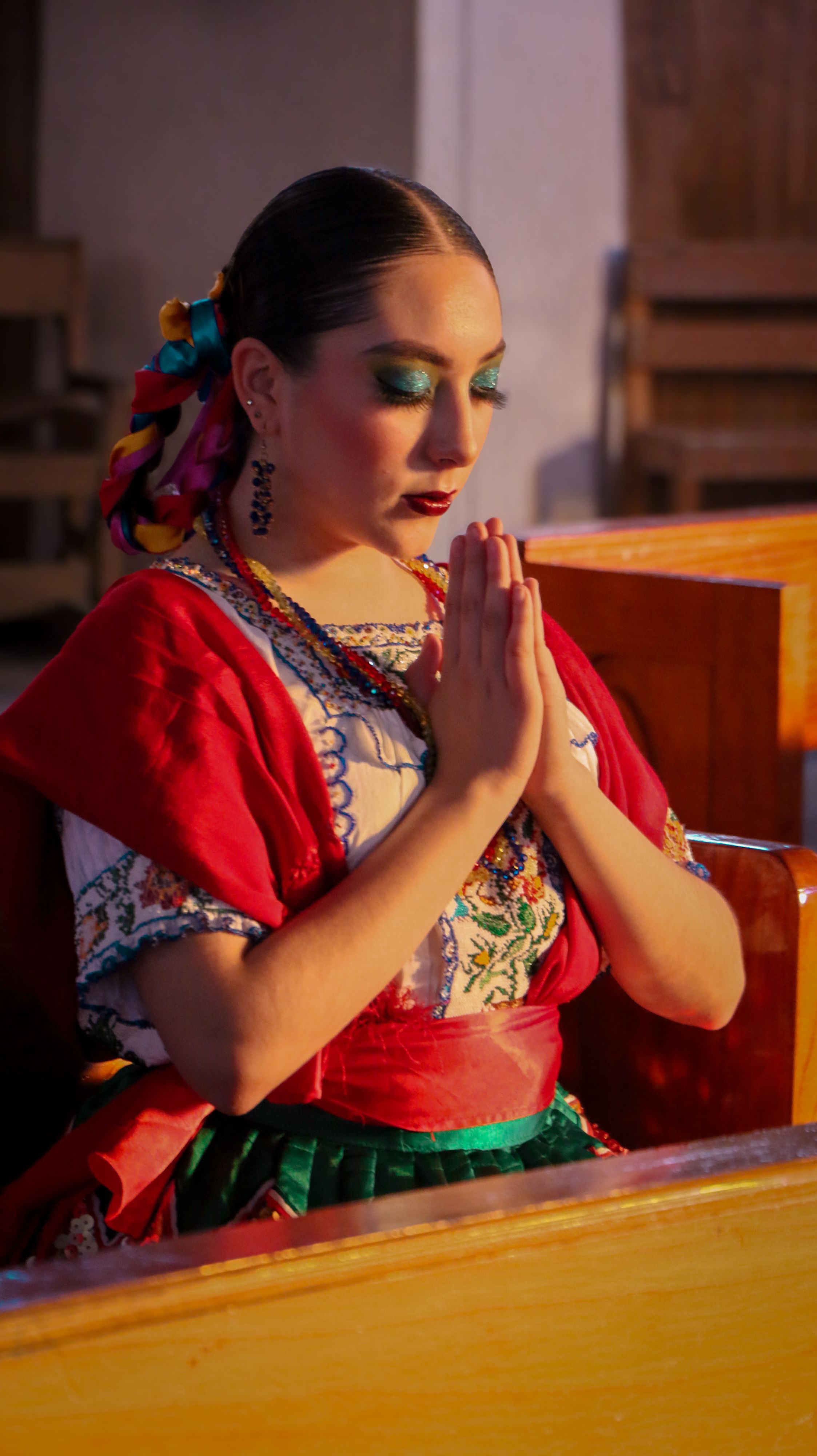 A woman in traditional attire prays with eyes closed, showcasing spirituality and culture.