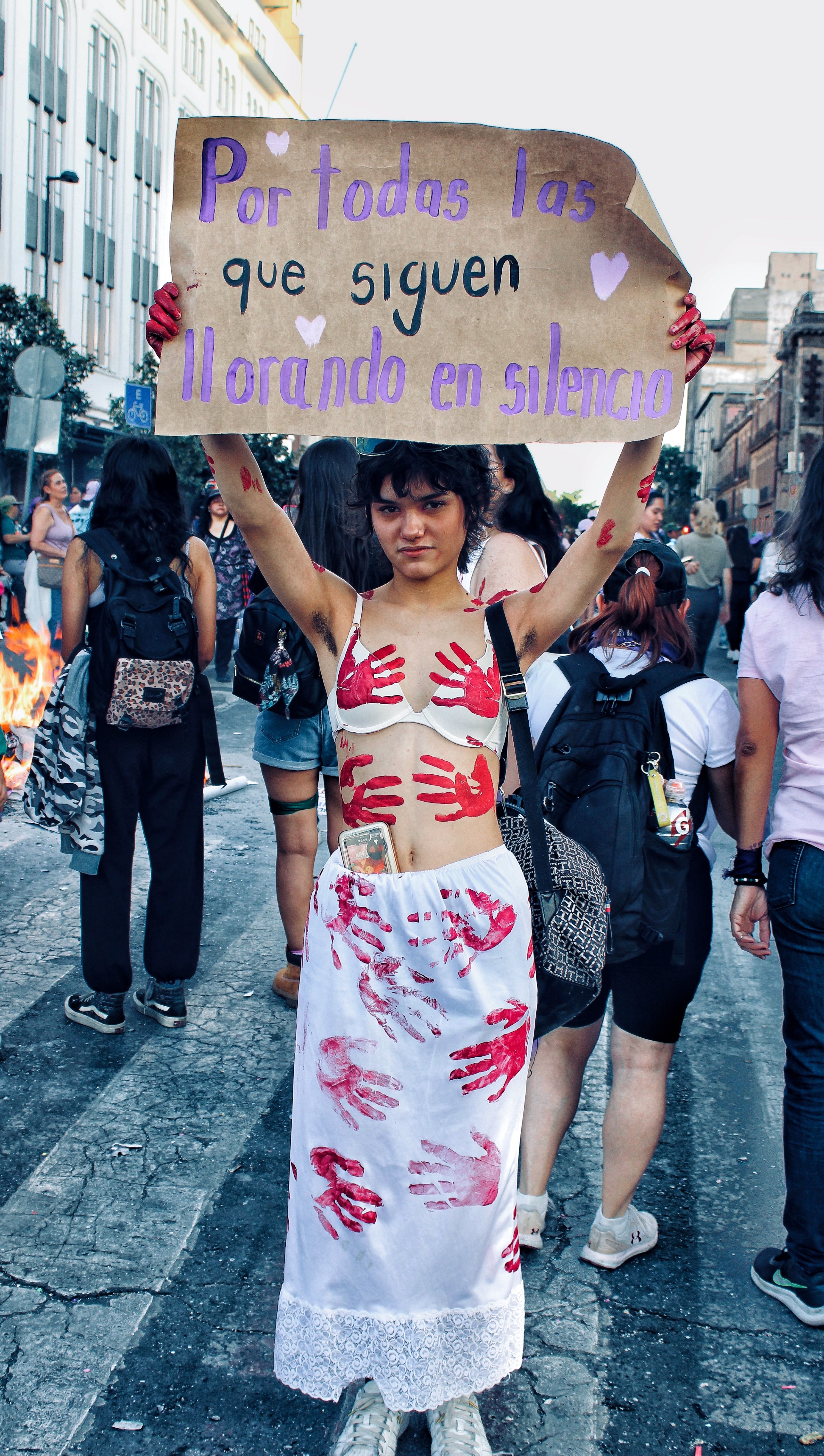 A woman protesting for silent voices in an urban setting, holding a powerful sign.