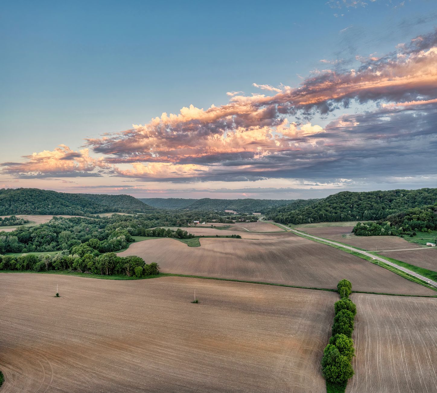 Stunning sunset aerial view of Weaver, MN's rural landscape showcasing fields and forests.