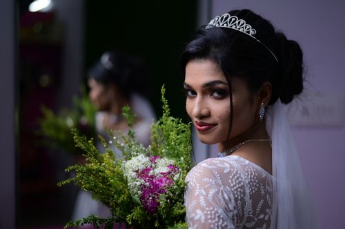 Free A stunning bride with a bouquet poses elegantly indoors, showcasing her captivating wedding attire and tiara. Stock Photo