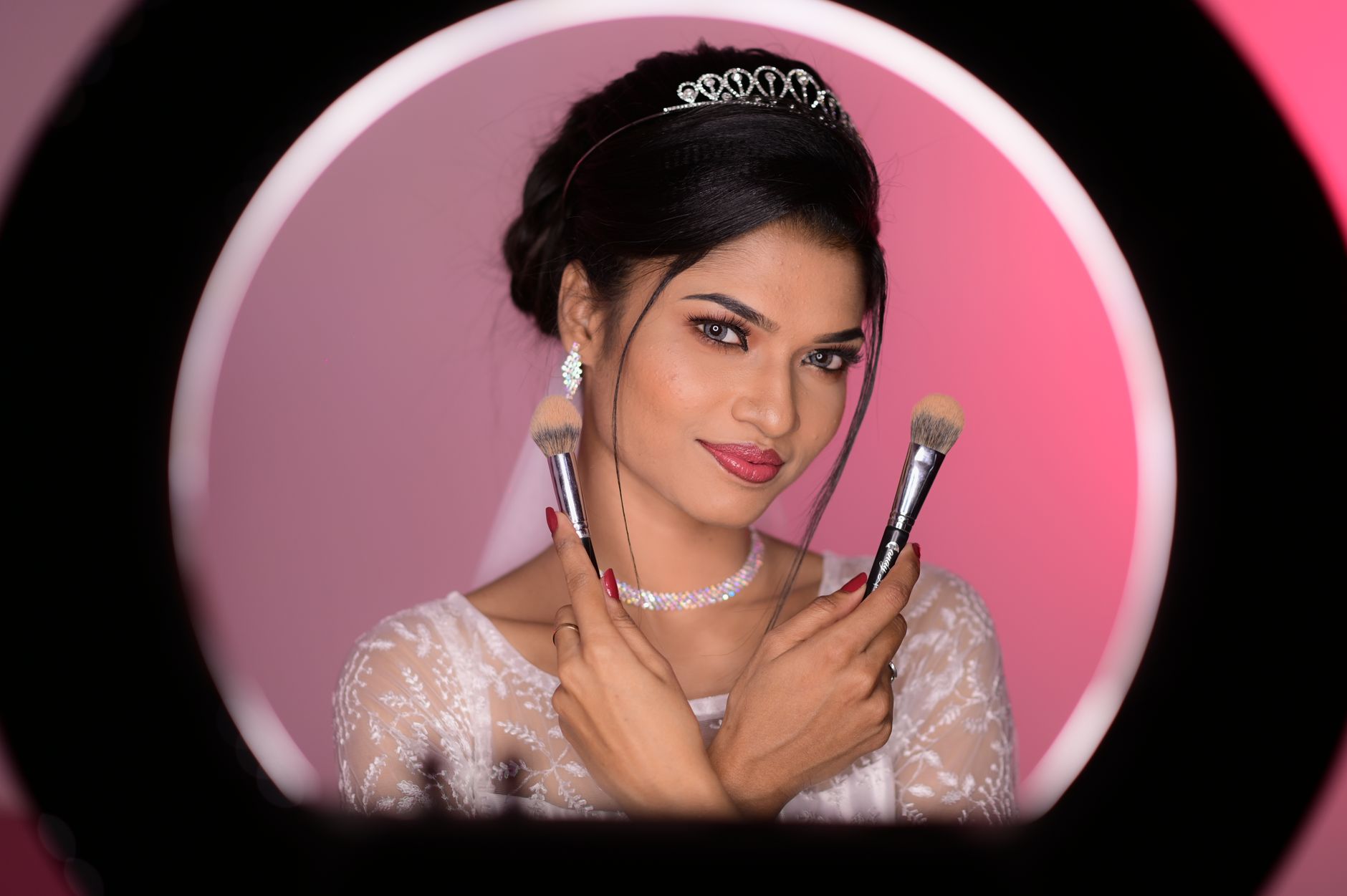 Stunning bridal portrait of a woman with makeup brushes in a pink-lit studio. Captured in Madrid.