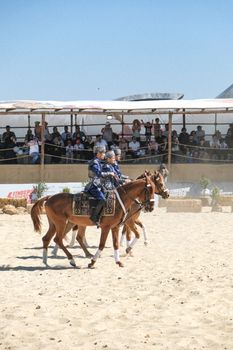 Performers on horseback displaying traditional costumes at an outdoor festival.