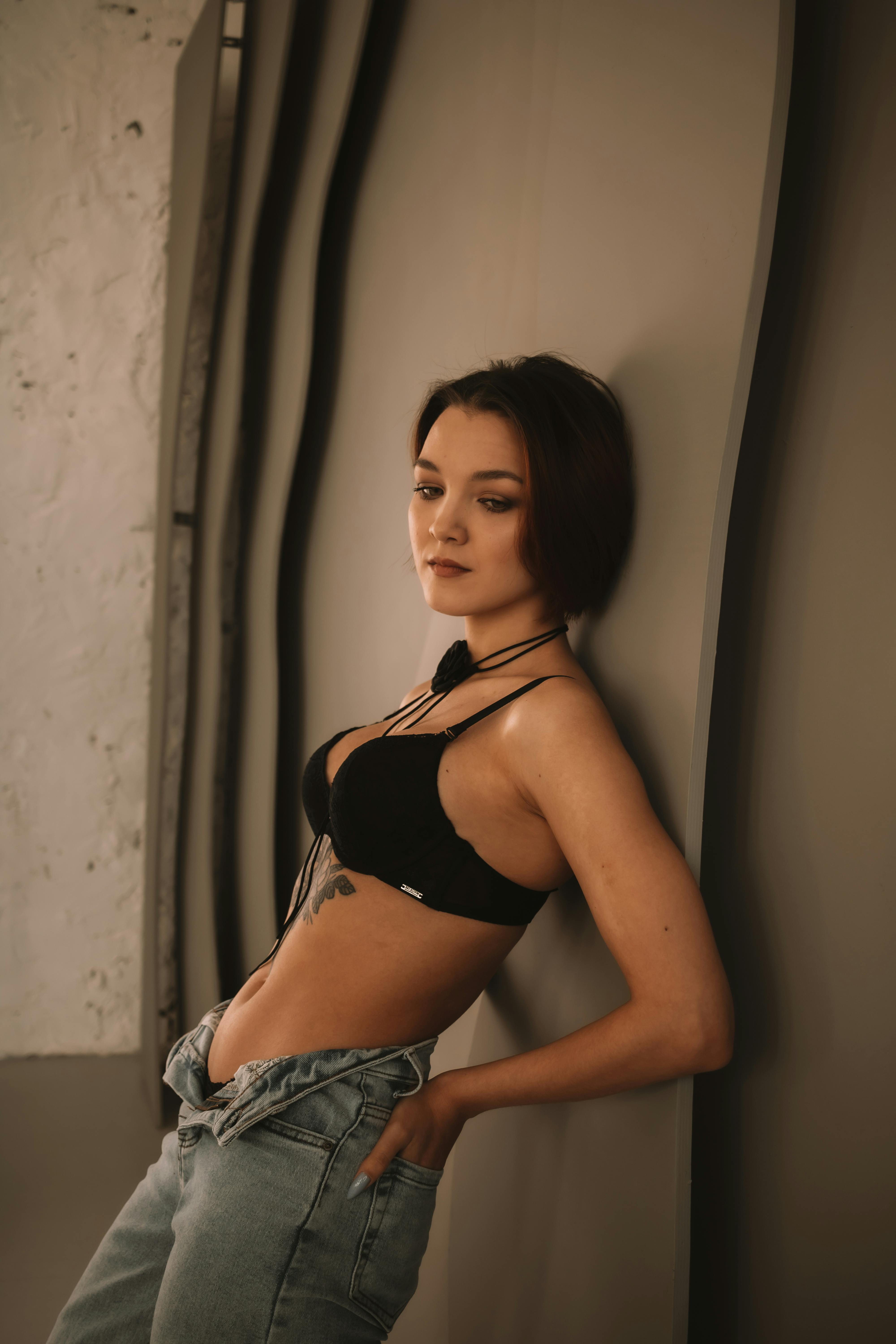 Free Fashionable woman in black bra posing against an artistic wall indoors. Stock Photo