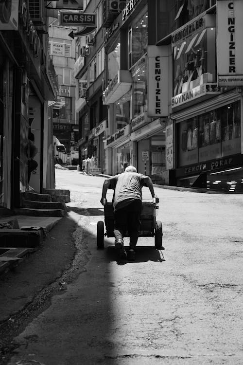 A man pushing a cart down a narrow alley