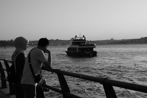 Free Two people observing a boat on Istanbul's Bosphorus in black and white. Stock Photo