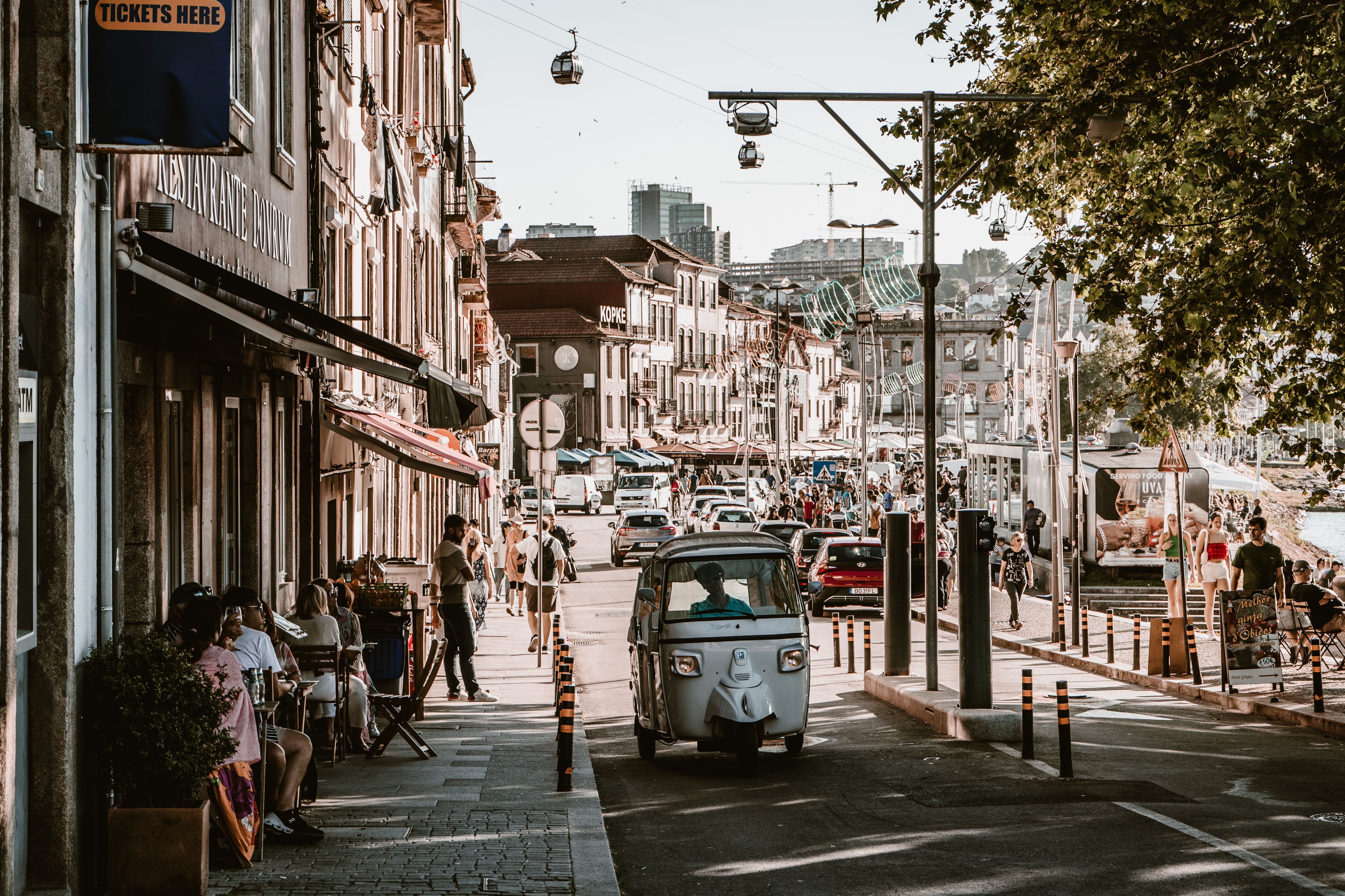 Vibrant urban street view in Porto, Portugal, capturing lively city life with people, traffic, and cable cars.