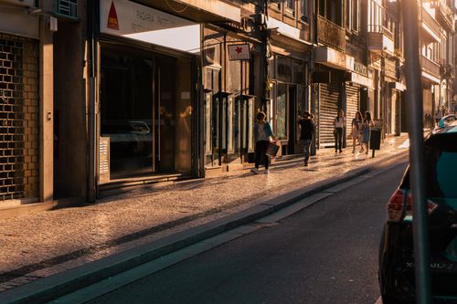 Free People walking along a sunlit street in Porto, Portugal during a vibrant urban evening. Stock Photo