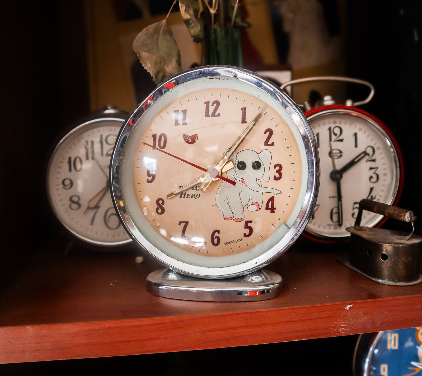 A collection of vintage analogue alarm clocks displayed on a wooden shelf, evoking nostalgia and timelessness.
