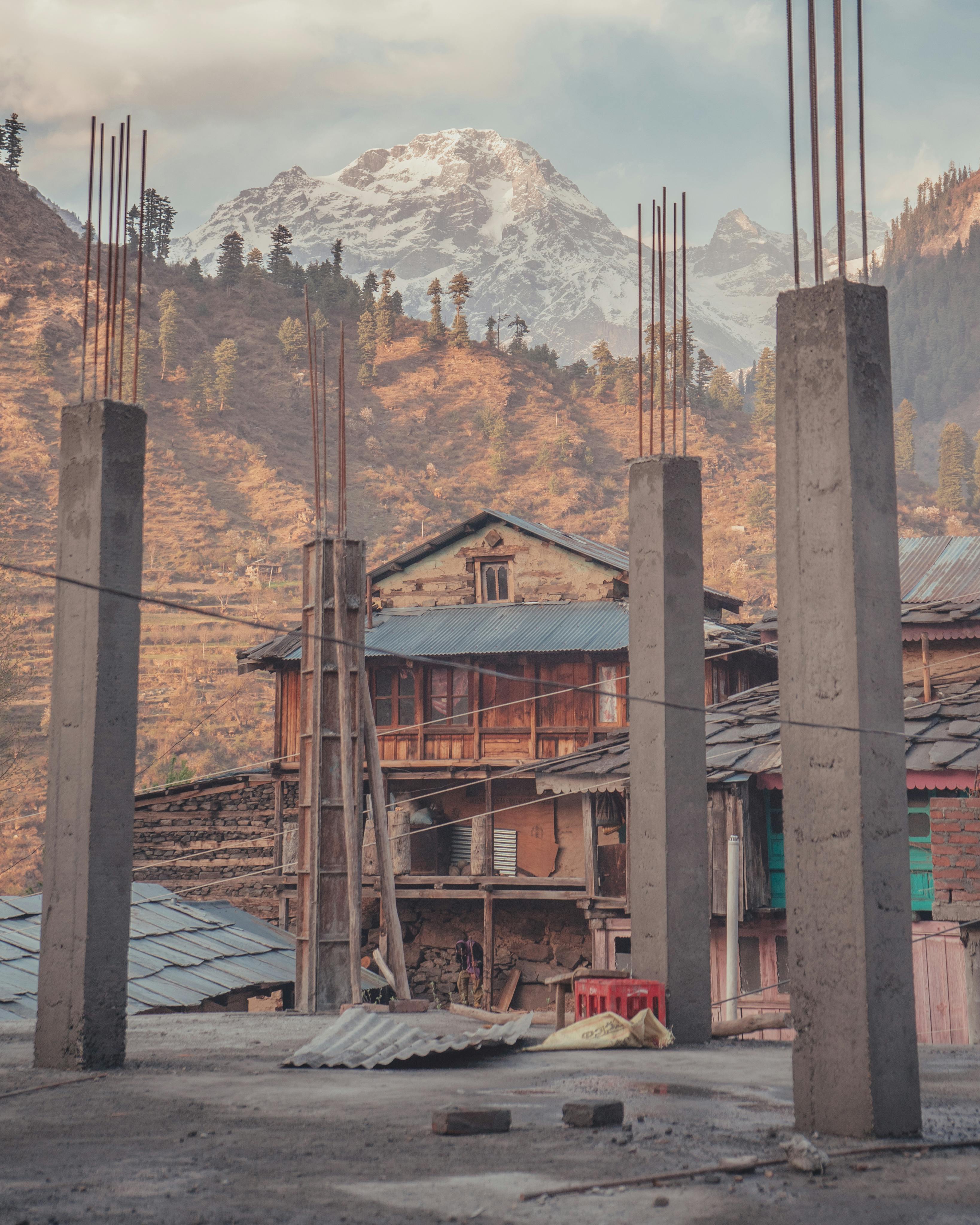 Rustic architecture meets new construction against the backdrop of Mandi's mountains. | Indian Village Development