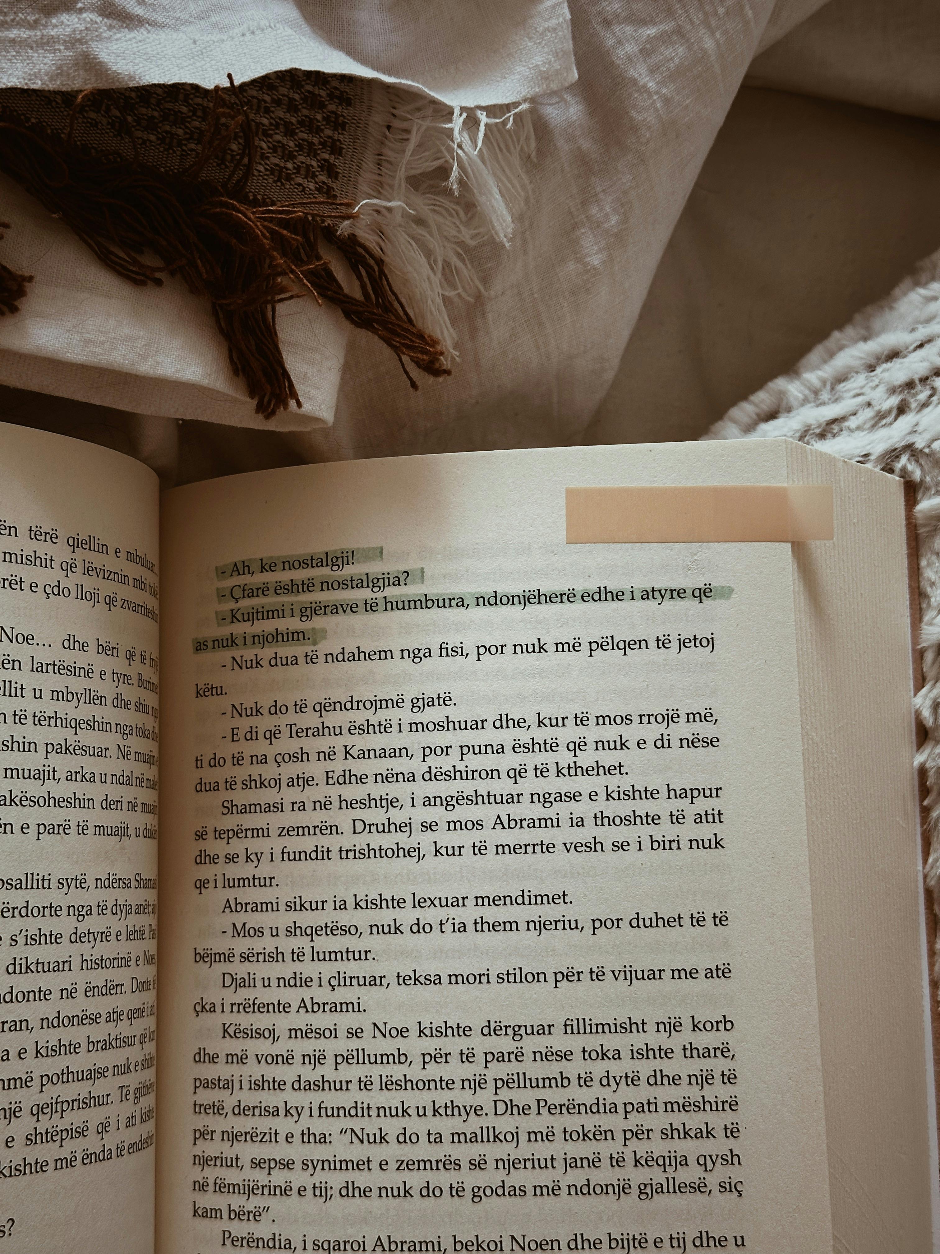 Close-up of an open book with highlighted text on a cozy fabric background, suggesting a reading nook.