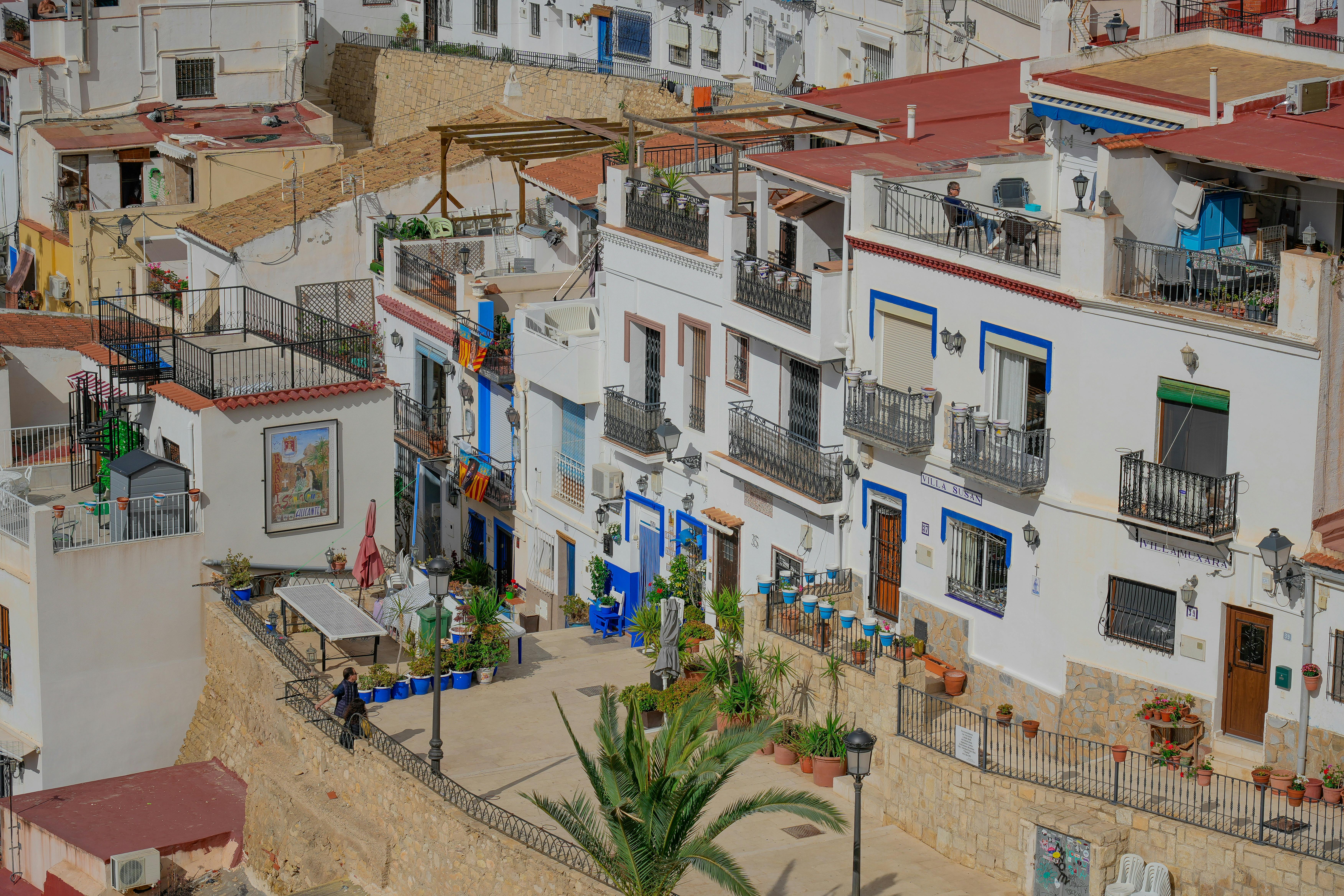 Vibrant street in Alicante, Spain with Mediterranean architecture and potted plants.