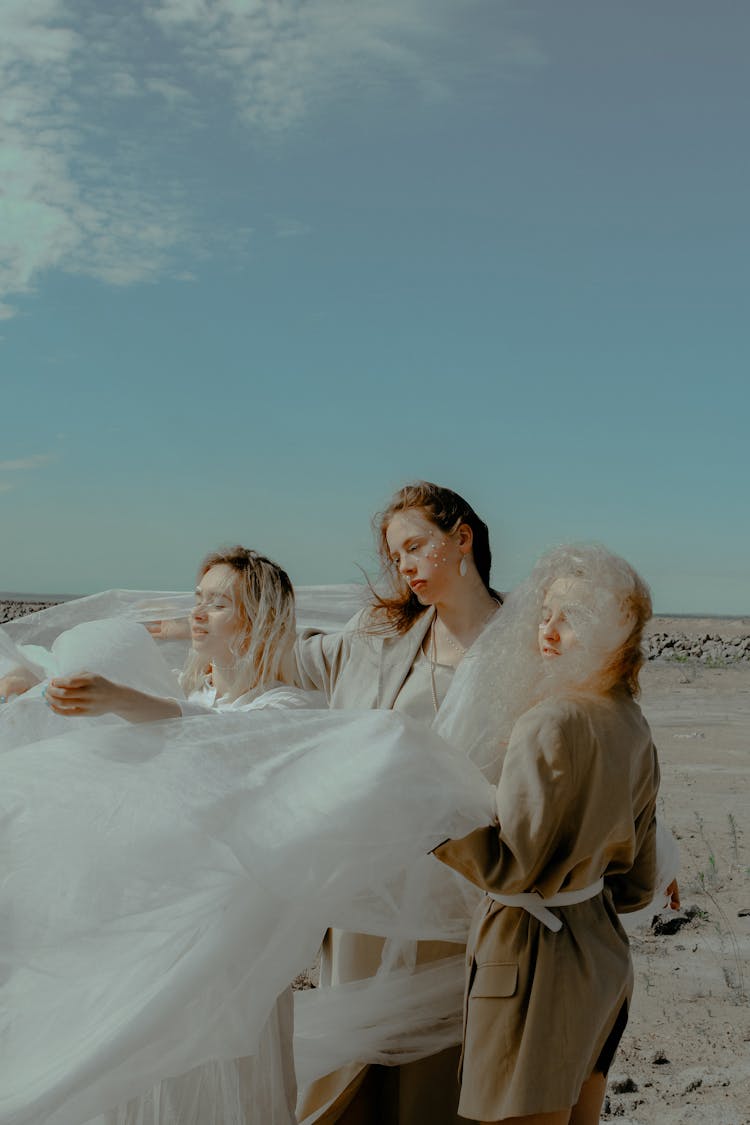 Three Women Holding A Textile