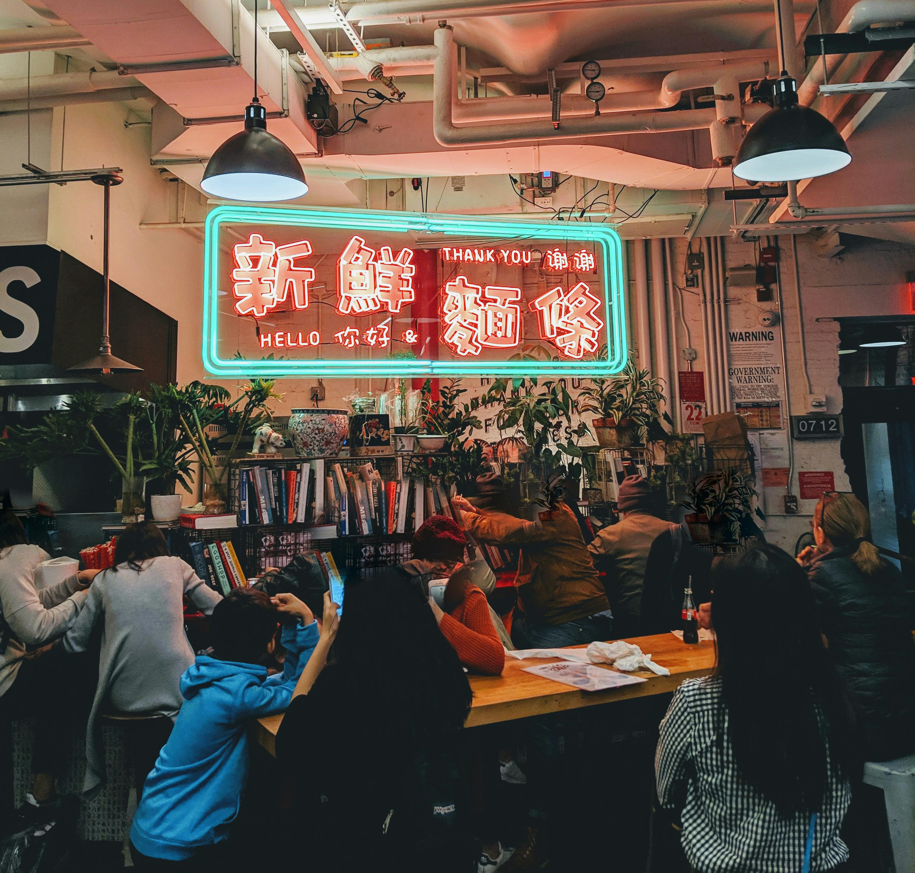 在一家城市咖啡馆里，人们正享受着舒适的聚会，那里有充满活力的霓虹灯标志和木桌布置