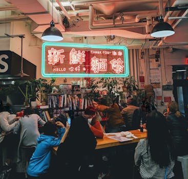 在一家城市咖啡馆里，人们正享受着舒适的聚会，那里有充满活力的霓虹灯标志和木桌布置