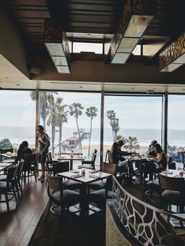 A modern restaurant interior with large windows offering a beautiful ocean view and stylish decor.