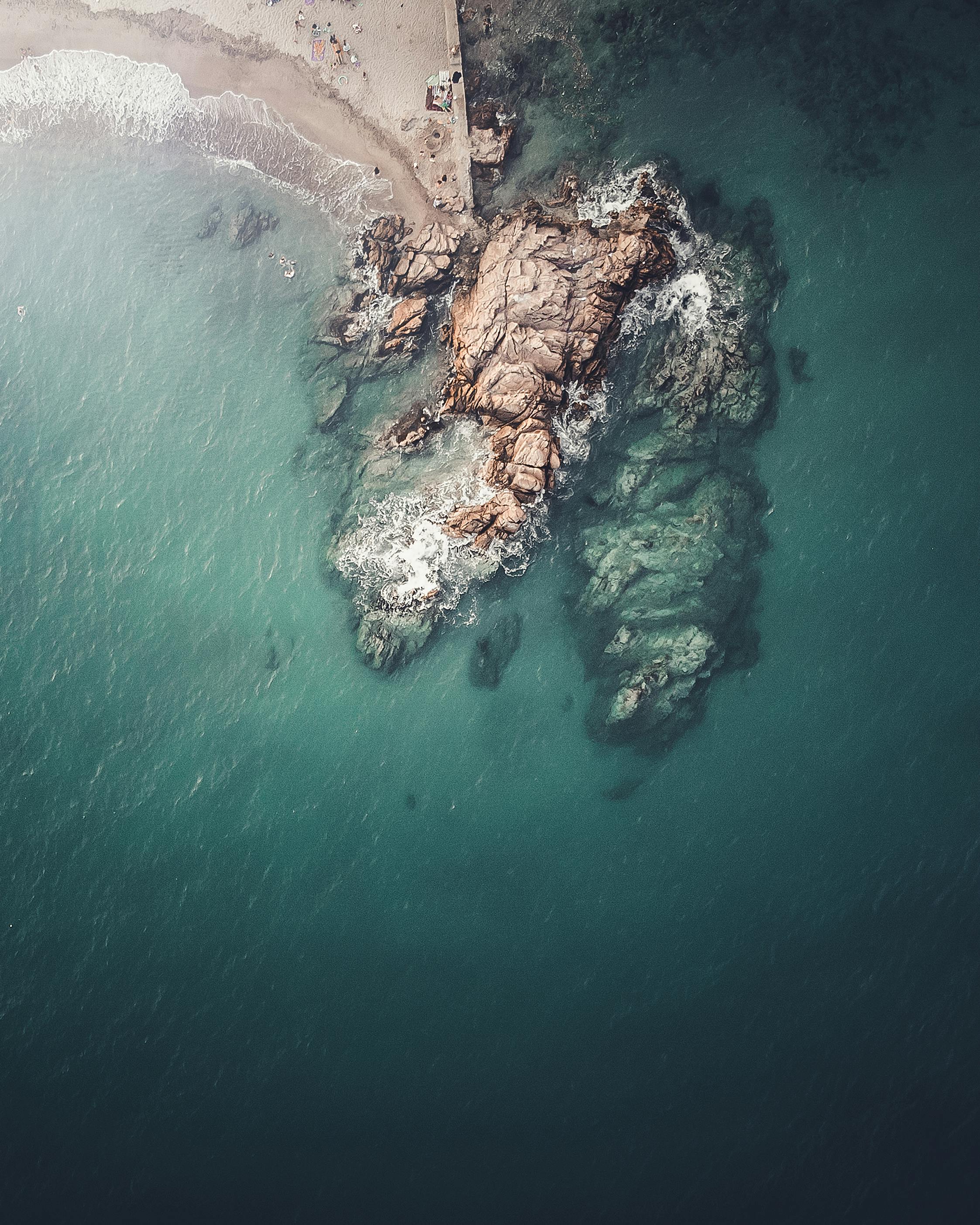 Drone shot of rocky shore in Cannes, France with turquoise ocean.