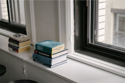 Stack of Books Near Glass Window