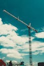 一台高耸的建筑起重机映衬在生机勃勃的蓝天下，云层散落，象征着城市的发展