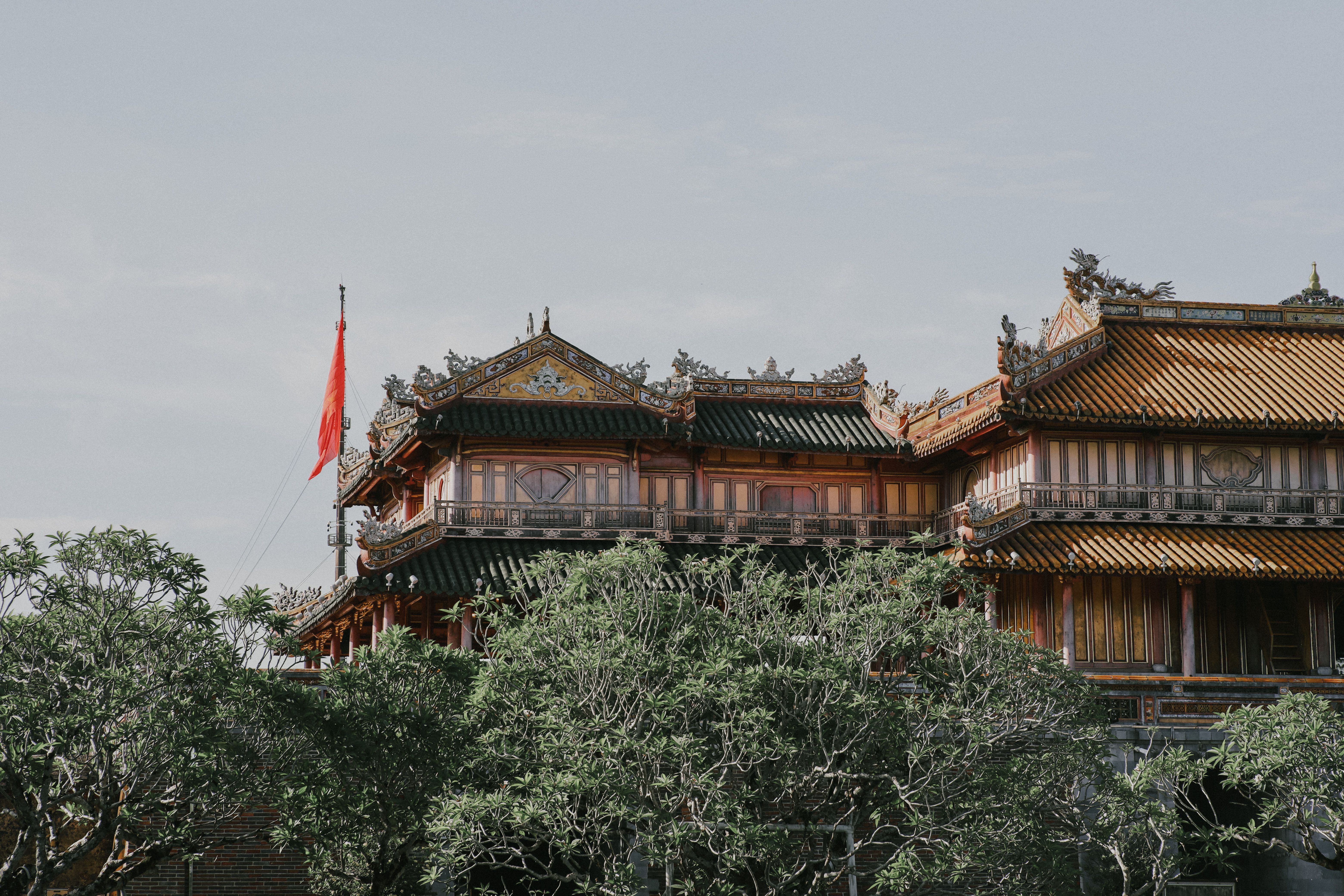 A chinese building with a red flag flying in the air · Free Stock Photo