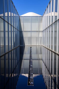 一座现代建筑的玻璃外墙在城市环境中反射着水