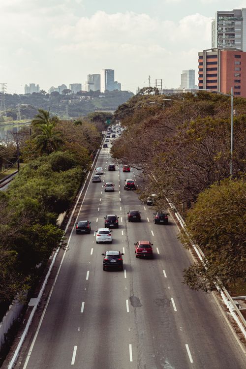 Free Aerial view of busy highway in São Paulo with urban skyline and surrounding greenery. Stock Photo