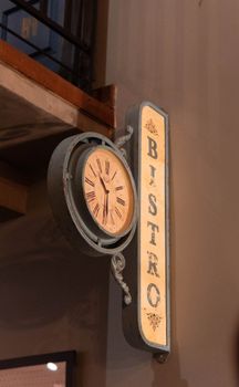 A vintage bistro sign featuring an old-fashioned clock with Roman numerals, adding elegant charm.