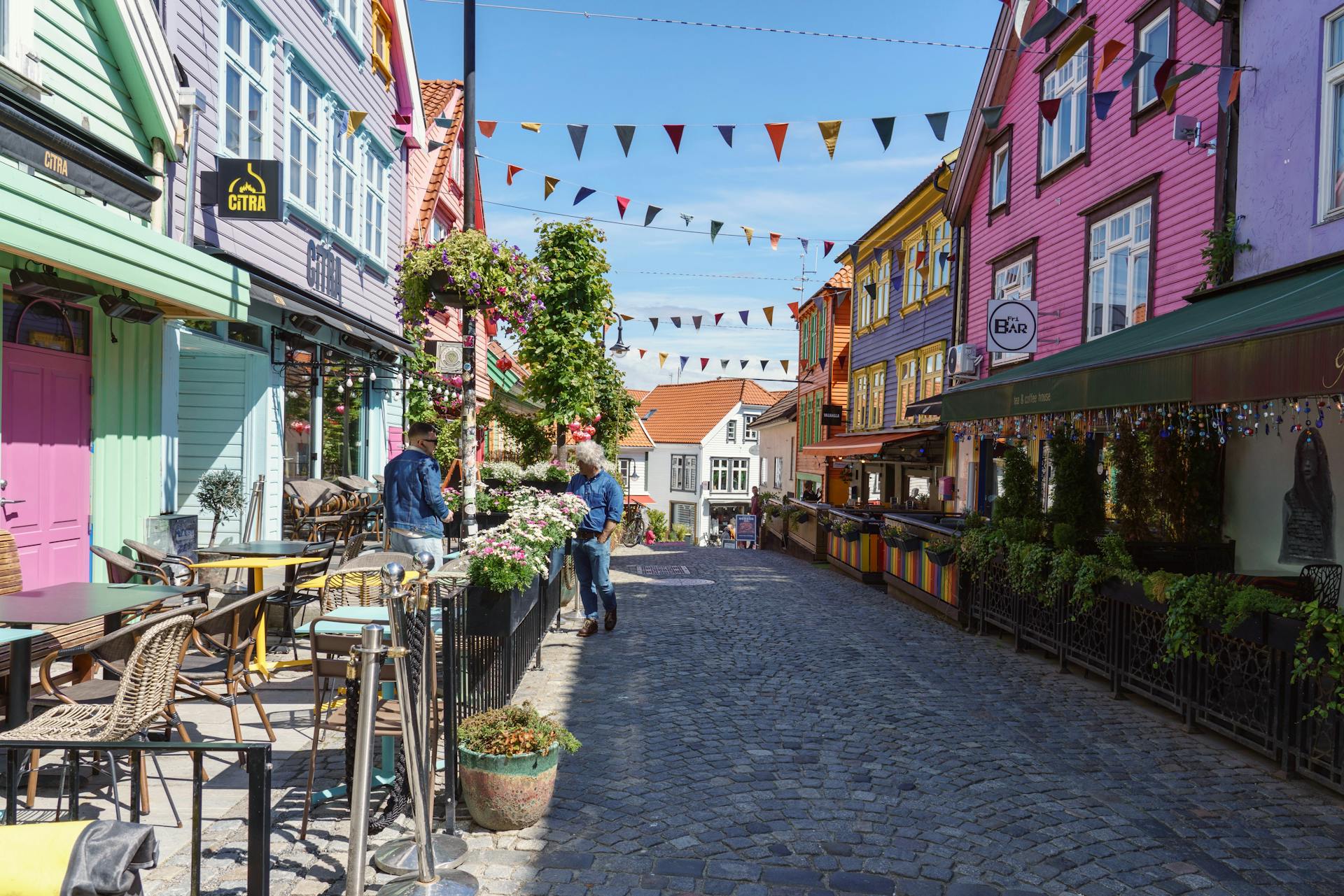 Vibrant street scene in Stavanger featuring colorful buildings and outdoor dining on a sunny day.