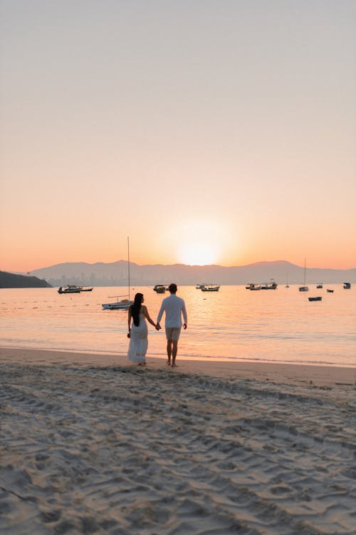 Free A couple walking on the beach at sunset Stock Photo