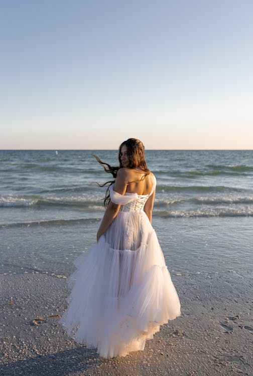 Free A woman in a wedding dress standing on the beach Stock Photo