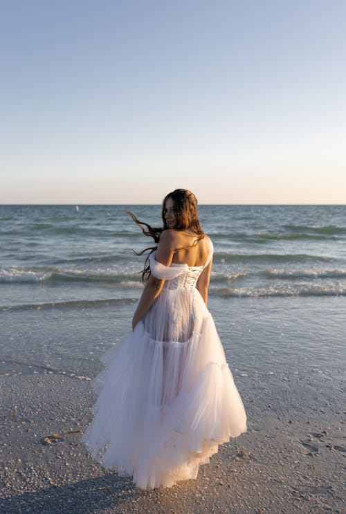 Free A woman in a wedding dress standing on the beach Stock Photo