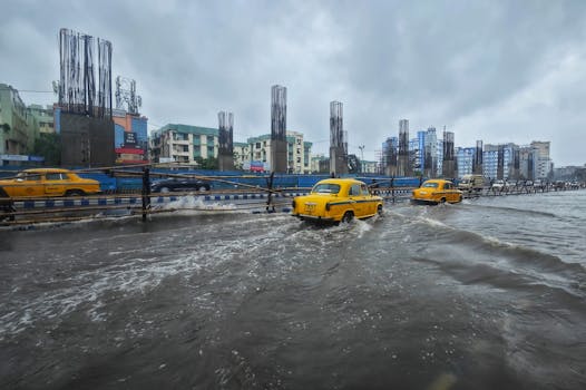 Yellow taxis driving through rainy, flooded streets of Kolkata, India during a heavy monsoon.
