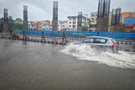A car navigates a flooded street in Kolkata, India after heavy rain, showcasing urban challenges.