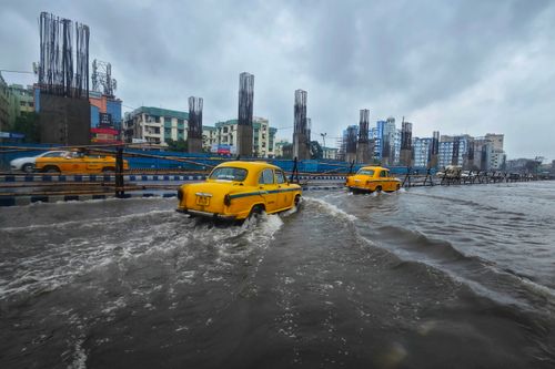 Free Yellow taxis navigate flooded streets in urban Kolkata on an overcast day. Stock Photo