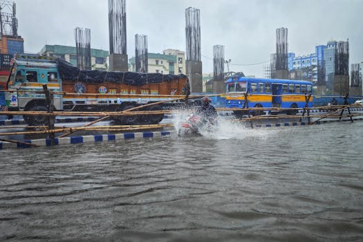 A motorbike navigates a flooded street in Kolkata, India, amidst urban traffic.