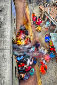 Blurred motion of people boarding a train at Kolkata station, capturing urban hustle.