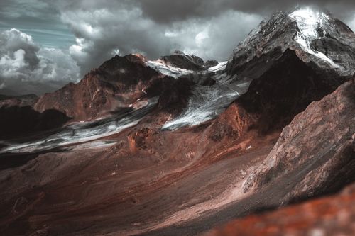Free Stunning view of rocky mountains with snow and clouds at sunset, perfect for nature and travel themes. Stock Photo