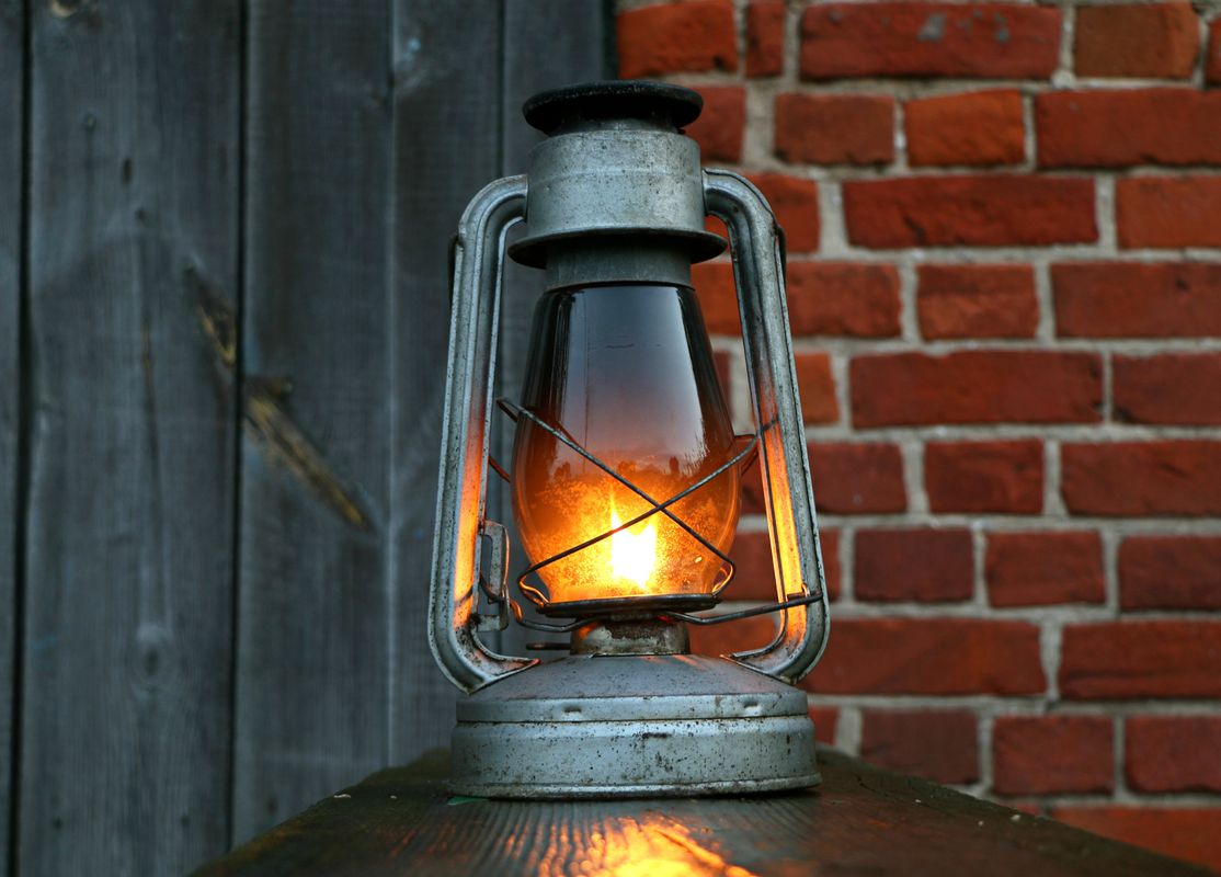 An old oil lantern burning against a brick wall - Brotherly Kindness, The Family Love of the Church