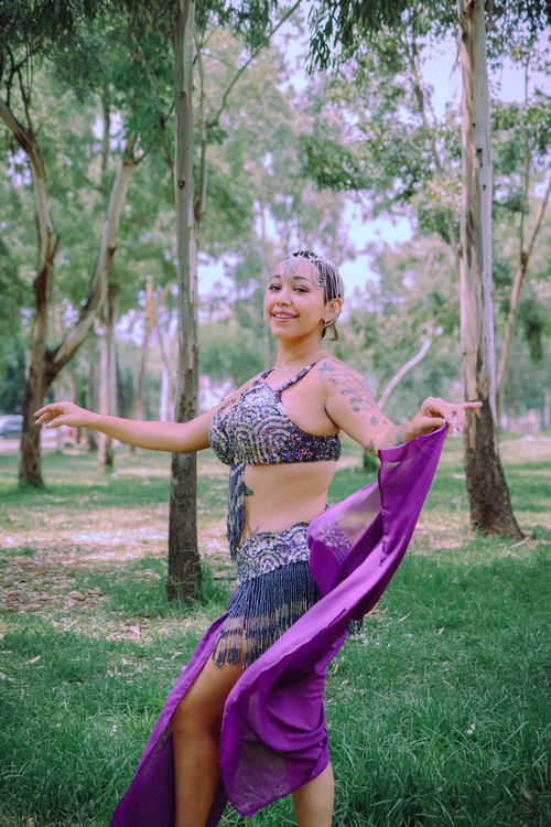 Free A happy woman in a belly dance costume with tattoos enjoys a sunny day in a park. Stock Photo