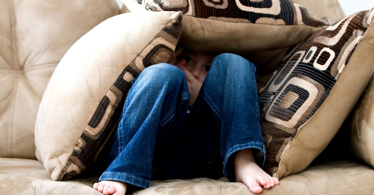 Rüyada Korkuyu Hissetmek - Rüya Tabiri ve Anlamı - A child crouched under cushions on a couch, conveying a sense of playfulness or fear.